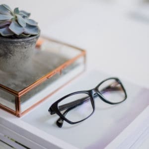 A pair of glasses sits on top of a stack of books.