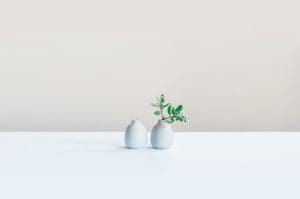 Two small white vases on a white table.