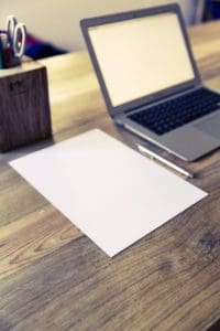A white sheet of paper on a wooden desk.